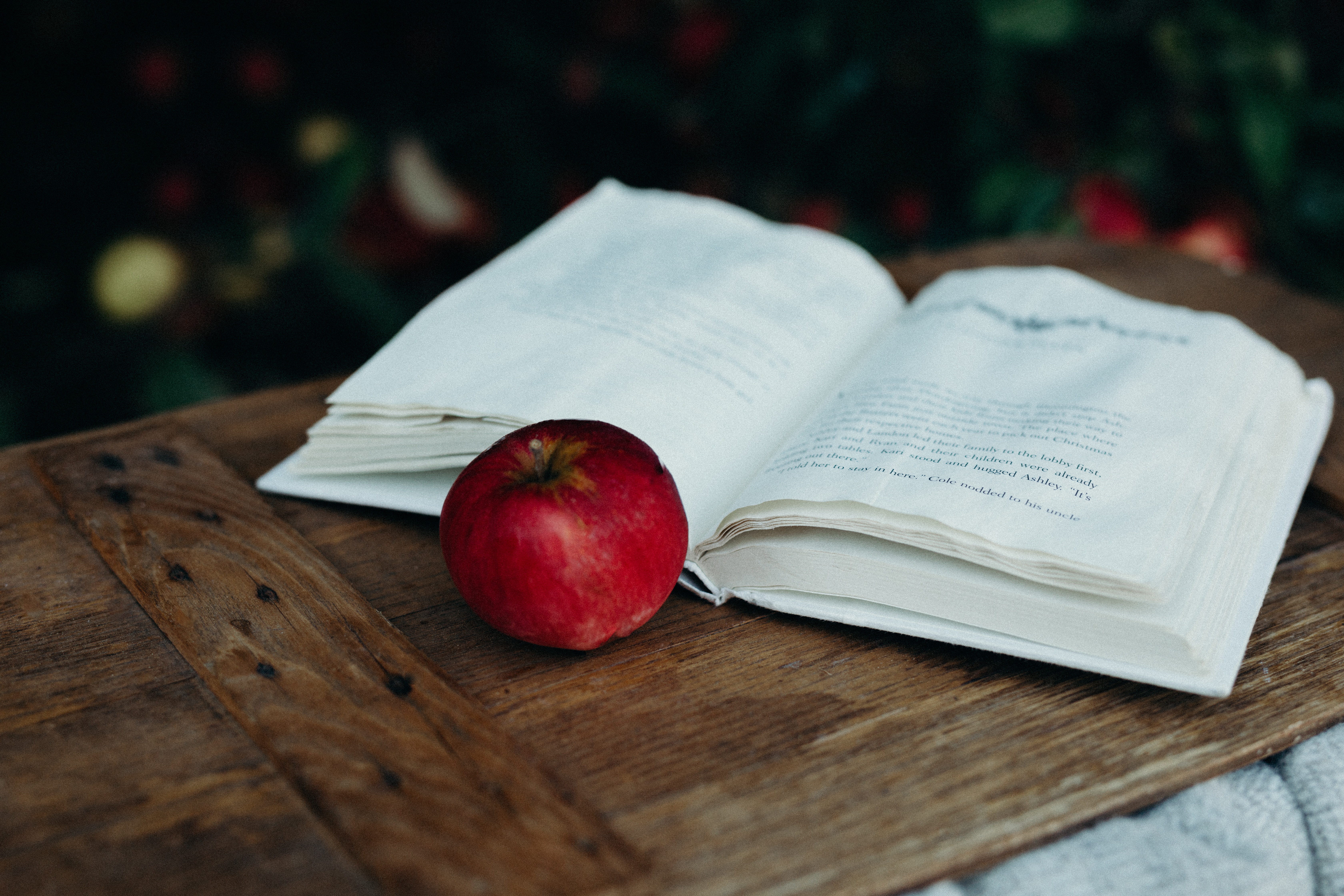 Livre ouvert sur une planche en bois avec une pomme rouge